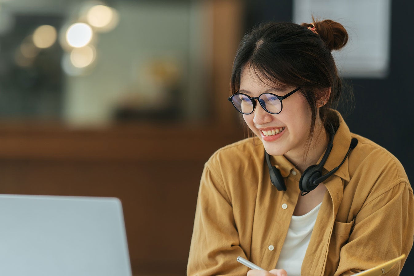 Student wearing headphones smiling at laptop screen.